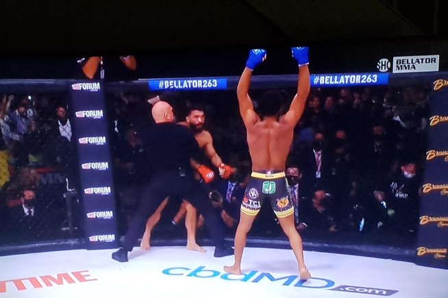 AJ McKee raises his hands after winning the Bellator Featherweight title